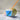 Eco-friendly bamboo straw in a blue drink on sandy beach with seashells.